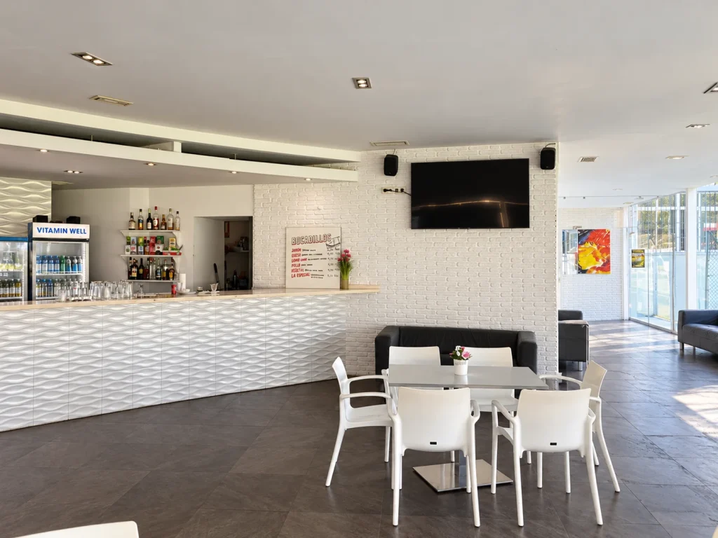 Barra de la cafetería de La Colina y zona de mesas junto a los ventanales.